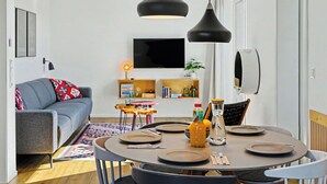 Un saló modern amb un sofà gris, una taula de dinar preparada per a quatre persones i dues làmpades penjants.