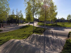 Ein Park mit einer Beton-Skateanlage, grünem Rasen und Bäumen.