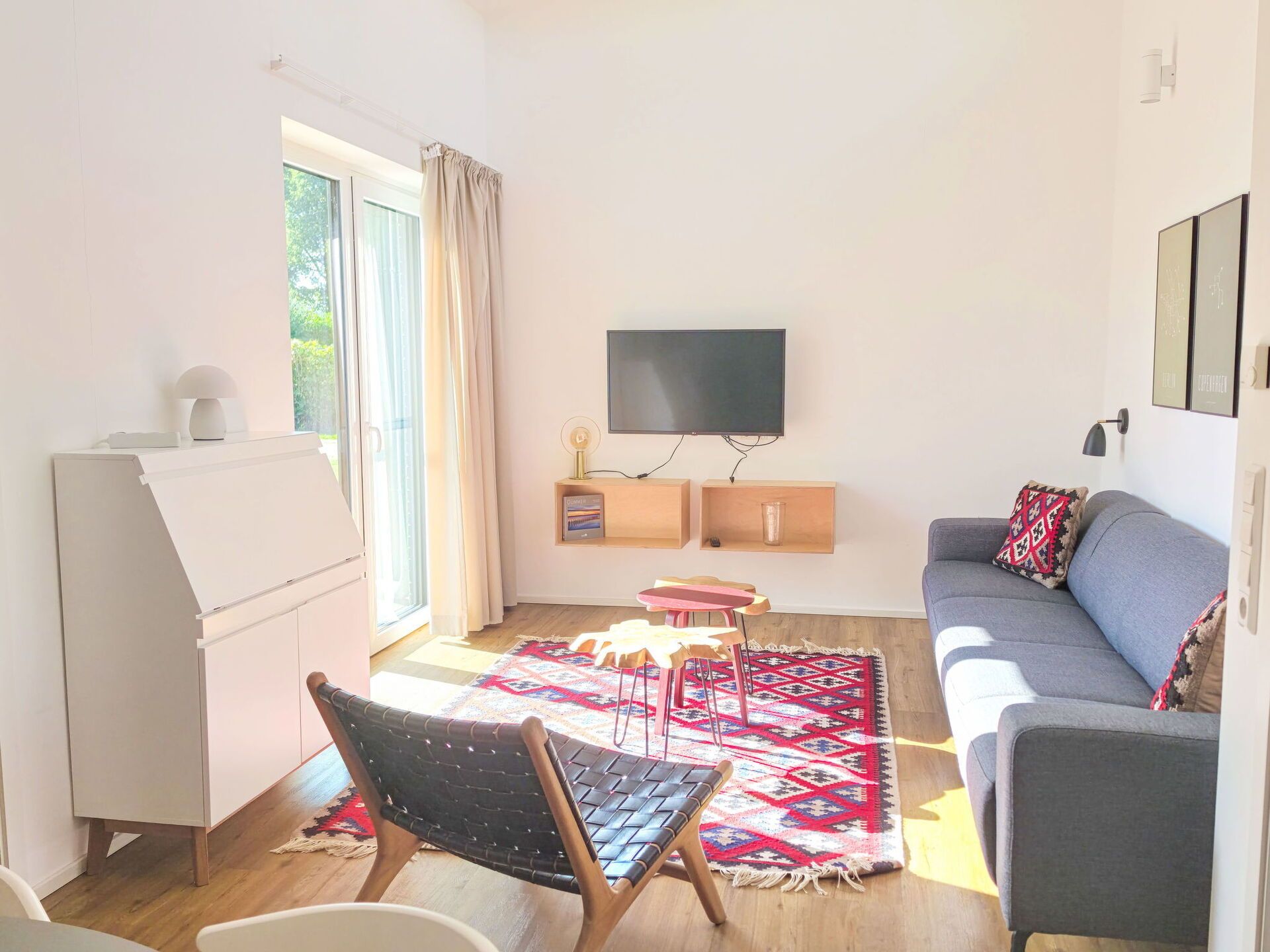 A living room with a sofa, a TV, a small table, a chair, and a patterned rug.