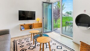 Een moderne woonkamer met een flatscreen televisie, een bank, twee kleine ronde tafels en een kamerkleed met een patroon.