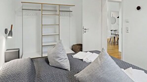 A bedroom with a bed, pillows, a wardrobe, a bedside lamp, and a view into another room. - Stunning private villa for 6 guests with WIFI, TV and terrace (Diepholz)