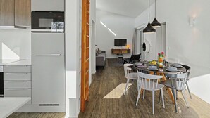 Cozinha moderna com armários brancos, micro-ondas embutido e uma escada de madeira.