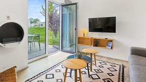 Ein modernes Wohnzimmer mit Fernseher, Kamin, Glastür zu einem Balkon und einem gemusterten Teppich.