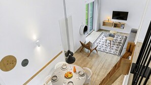 Ein modernes Interieur mit einer Essecke, die einen runden Tisch, weiße Stühle und eine Obstschale zeigt.