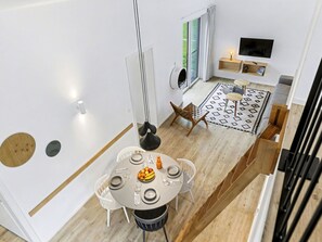 A modern interior with a dining area featuring a round table, white chairs, and a fruit bowl. - Beautiful private villa for 6 people with hot tub, pool, WIFI, TV, terrace and pets allowed (Diepholz)
