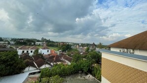 A residential area with houses, some greenery, and a cloudy sky. - Vrata Hotel Yogyakarta (Kalasan)