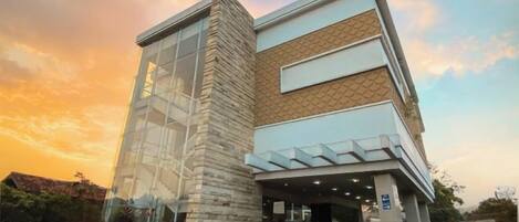 A modern building with a glass facade and a brick section, featuring a flat roof and a covered entrance.