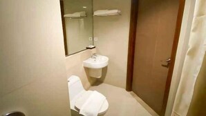 A small, compact bathroom with a toilet, sink, and a mirror. - Vrata Hotel Yogyakarta (Kalasan)