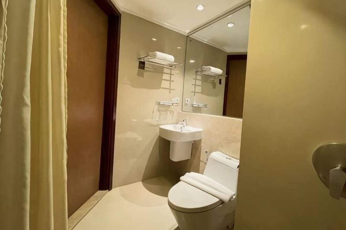 A compact bathroom with a toilet, sink, and mirror.