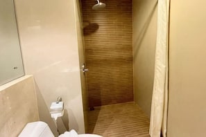 A narrow bathroom with a wooden shower enclosure, a toilet, and a sink. - Vrata Hotel Yogyakarta (Kalasan)