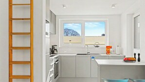 Une petite cuisine équipée d’une fenêtre, d’une machine à café, d’une bouilloire et d’une boîte de céréales Kellogg’s.
