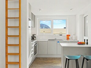 Eine kleine Küche mit Fenster, einer Kaffeemaschine, einem Wasserkocher und einer Flasche Kellogg's-Cerealien.