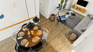 Un salon moderne comprenant un coin repas, un canapé, un téléviseur et une fenêtre donnant sur un beau paysage.