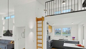 Una cocina moderna con una escalera de madera, un comedor con mesa y sillas, y vistas al exterior a través de una ventana.