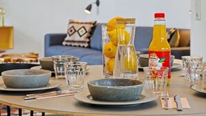 Ein Esstisch, gedeckt mit Tellern, Gläsern und einer Flasche Orangensaft.