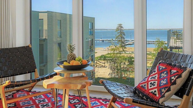 A balcony with two chairs, a small table with fruit, and a view of the sea and buildings. - Lovely apartment for 6 people with WIFI, TV, balcony and pets allowed (Diepholz)