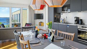 A modern kitchen with a built-in oven, a dining area with a table set for two, and a large window overlooking the sea. - Lovely apartment for 6 people with WIFI, TV, balcony and pets allowed (Diepholz)