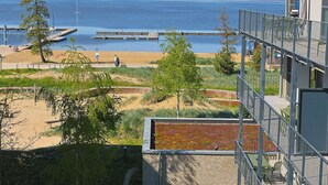 A view of a beach with a pier, a building with a balcony, and wind turbines in the distance. - Lovely apartment for 6 people with WIFI, TV, balcony and pets allowed (Diepholz)