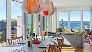 A dining area with a table set for four, large windows with a view of the sea, and a balcony with outdoor seating. - Lovely apartment for 6 people with WIFI, TV, balcony and pets allowed (Diepholz)