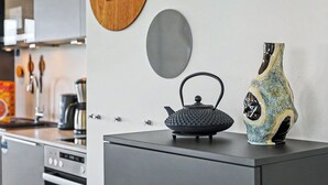 Una cocina con un hervidor, un florero y una decoración de pared de madera.
