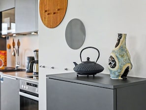 Eine Küche mit Wasserkocher, einer Vase und einer Holzdeko an der Wand.