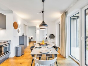 Eine moderne Küche mit Essbereich, integriertem Backofen und einem großen Fenster mit Vorhängen.