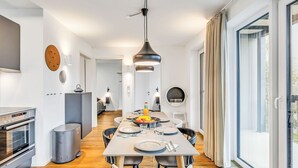 Een moderne keuken met een eethoek, een inbouwoven en een groot raam met gordijnen.