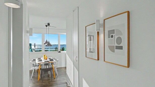Eine moderne Küche mit Essbereich, großen Fenstern und Kunstwerken an der Wand.