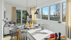 Eine moderne Küche mit Essbereich, großen Fenstern und Blick ins Freie.