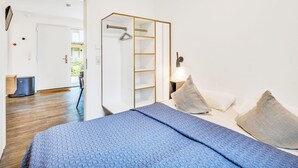 A bedroom with a bed, pillows, a wardrobe, and a nightstand. - Beautiful apartment for 4 people with WIFI, TV, terrace and pets allowed (Diepholz)