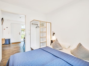 Ein Schlafzimmer mit Bett, Kissen, Kleiderschrank und Nachttisch.