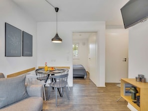 Ein modernes Apartment mit Essbereich, einer Couch, einem Fernseher und einem Bücherregal.