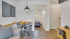 Un apartamento moderno con comedor, sofá, televisor y estantería.