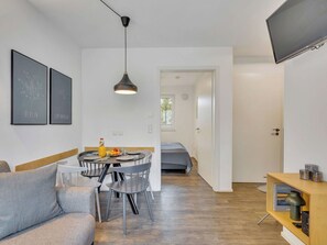 Ein modernes Apartment mit Essbereich, einer Couch, einem Fernseher und einem Bücherregal.
