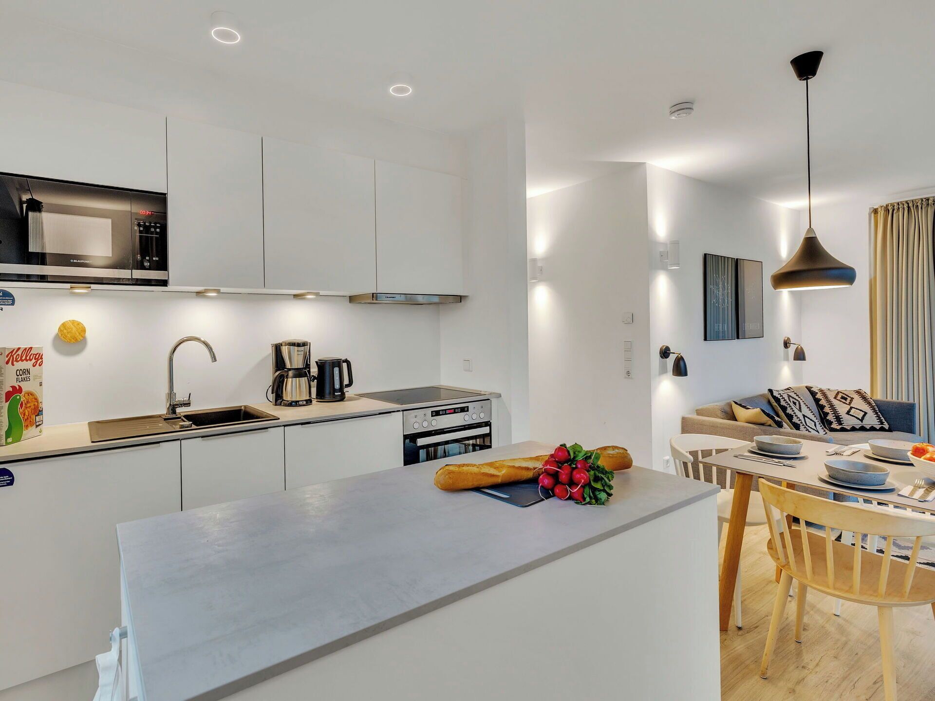 A modern kitchen with a central island, built-in appliances, and a dining area with a table and chairs.