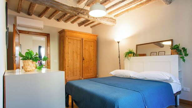 A bedroom with a bed, wooden wardrobe, and a mirror. - Beautiful apartment for 4 people with A/C, WIFI, TV and pets allowed (Pisa)