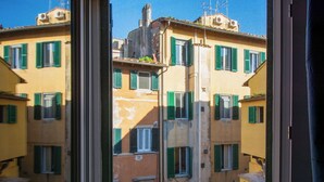 A view through a window of a building with multiple floors, featuring balconies with red tiles and green shutters. - Beautiful apartment for 4 people with A/C, WIFI, TV and pets allowed (Pisa)