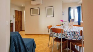 A dining area with a table set for four, framed pictures on the wall, and an air conditioning unit above. - Beautiful apartment for 4 people with A/C, WIFI, TV and pets allowed (Pisa)