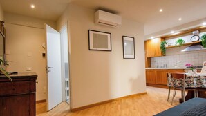 A modern apartment with a wooden floor, a dining area with a table and chairs, a kitchen with wooden cabinets, and a white door leading to another room. - Beautiful apartment for 4 people with A/C, WIFI, TV and pets allowed (Pisa)