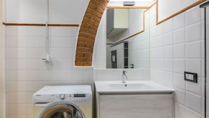 Un baño moderno con lavadora, lavamanos y espejo.