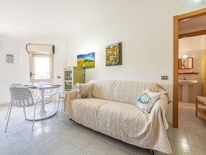 Ein Wohnzimmer mit einer Couch, einem Esstisch mit Stühlen und zwei Bildern an der Wand.