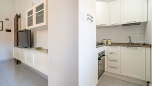 Una cocina moderna con armarios blancos, horno integrado y pileta de acero inoxidable.