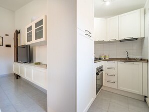 Eine moderne Küche mit weißen Schränken, einem Backofen und einer Spüle aus Edelstahl.