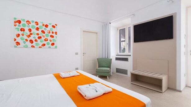 Une chambre d’hôtel avec un lit, un fauteuil vert, une télévision et une fenêtre.