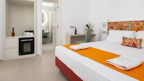 Habitación de hotel con cama, escritorio, espejo y minibar.
