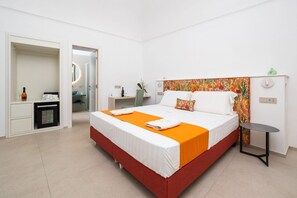 Ein Hotelzimmer mit Bett, Schreibtisch, Stuhl, kleinem Tisch und Spiegel.
