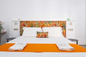 Ein Hotelzimmer mit einem Bett, zwei Nachttischen, einer Ablagefläche und einem dekorativen Kissen sowie einer orangefarbenen Bettdecke.