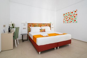 Una habitación de hotel con cama, escritorio, silla y una mesita.