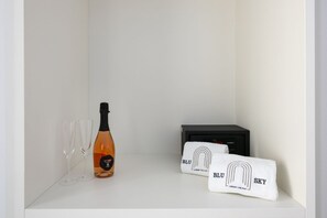 Un estante blanco con una botella de champán, dos copas y una toalla con el texto 'BLU SKY LUXURY PALACE'.