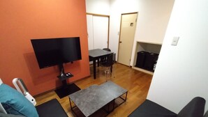 Un espacio habitable compacto con televisor, una mesa de comedor y un sofá.